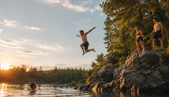 A swimmer leaping from a rock into a lake at sunset